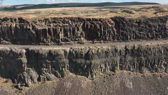 Side scrolling aerial shot of a highway embedded in a cliffside.