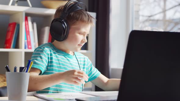 Boy is Doing  Homework at the Table. Cute Child is Learning at Home.