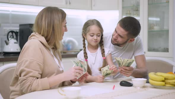 Joyful Caucasian Young Family Scattering Money in Slow Motion Resting in Kitchen at Home