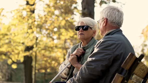 Senior Caucasian Man Spends Time with His Disabled Blind Wife in the Park Looking Back Disabled