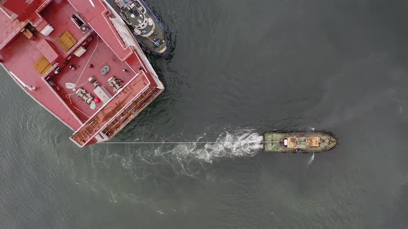 Aerial View Vertically Downward on a Tug Pulling a Vessel for Mooring By a Cable