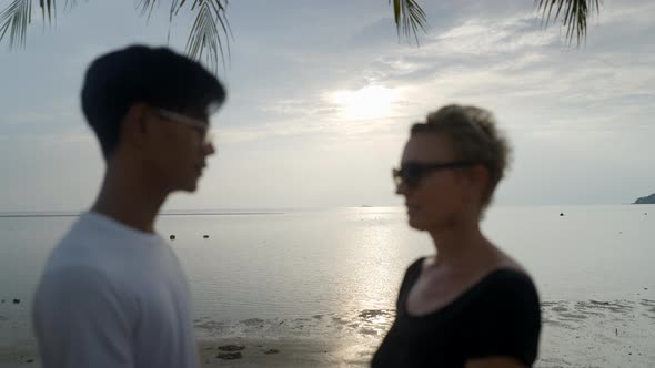 Interracial Couple with Age Differences Kissing Holding Hands at Sandy Beach at Sunset By the Sea