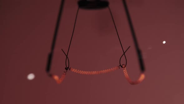 The Tungsten Filament in a Glass Lamp Closeup in Slow Motion on Red Background