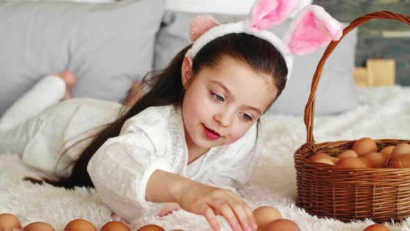 Happy girl playing with easter eggs in bed