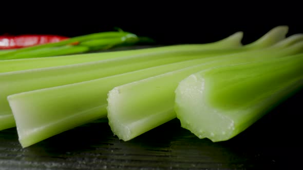 Row of Green Celery Stalks Lying on Black Board on Isolated Black Studio Background