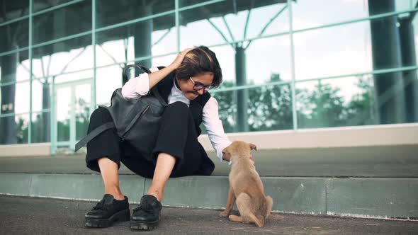 Young Beautiful Businesswoman Sitting on Street Stroking Puppy Business Centre Background