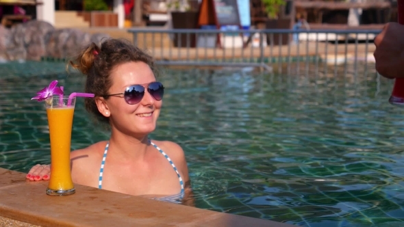 Happy Couple Drinking Cocktails In The Swimming