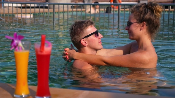 Couple Relaxing In Sunny Swimming Pool