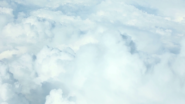 Airplane Flying Above Puffy Clouds