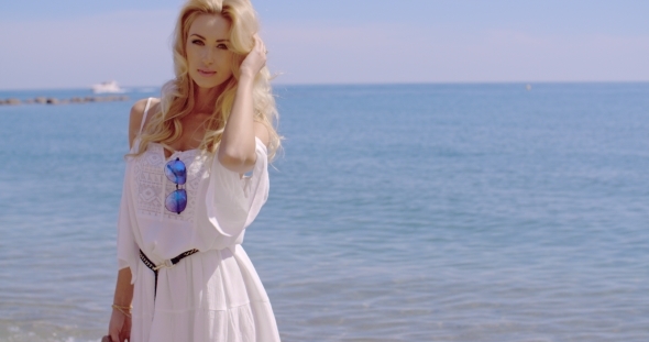 Blond Woman In White Sun Dress Standing On Beach