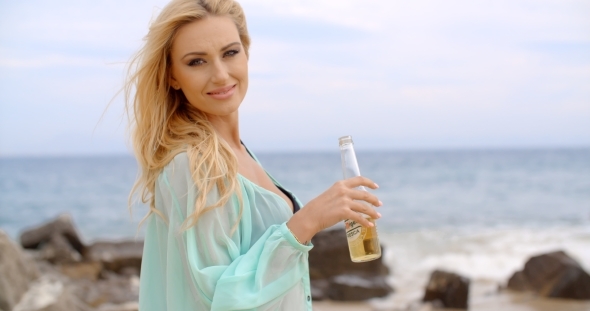 Blond Woman Holding Bottle Of Beer On Beach