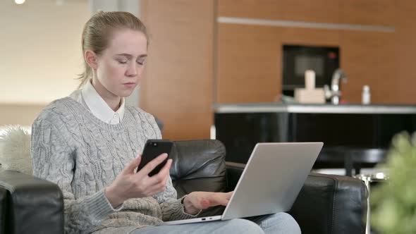 Young Woman Working on Laptop and Smartphone at Home 