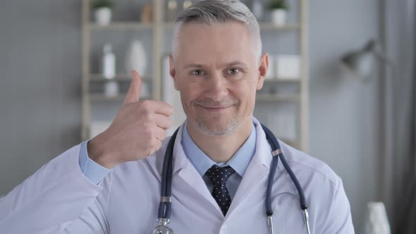 Thumbs Up By Positive Doctor with Grey Hairs