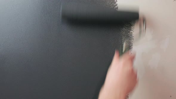 Roller paints the wall with gray paint