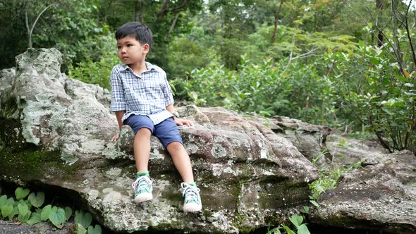 The boy sitting on a rock at the nature