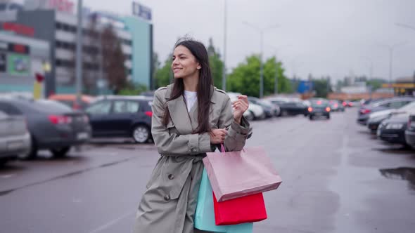 Female Shopaholic with Bags Walking Along Parking Lot to Her Car