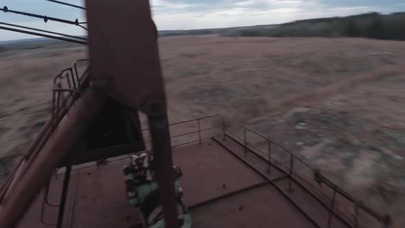 FPV Drone Flies Maneuverable Near Rusty Abandoned Walking Excavator