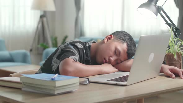 Tired Teen Boy Sleep On The Table At Living Room After Doing Home Work