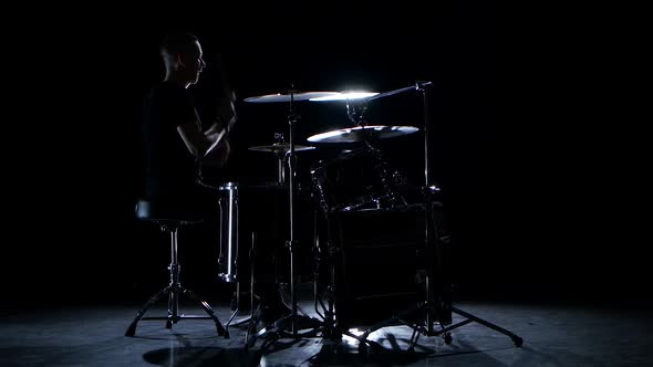 Drummer Plays Energetic Music on the Drum. Black Background. Side View