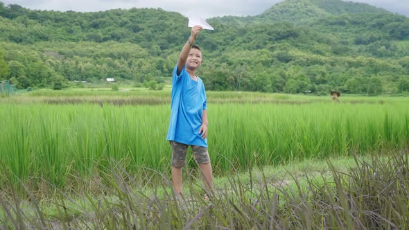 Boy Playing With Paper Airplane In Rice Field