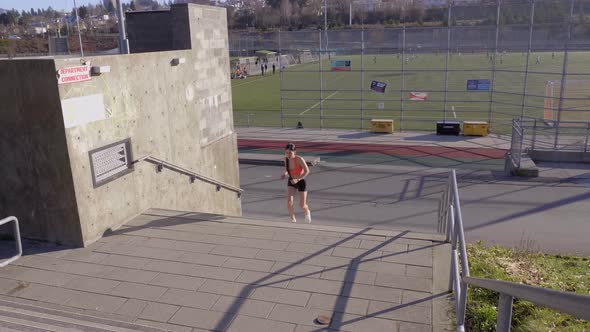 Young fit girl running up steps exercising outdoors Wide Shot