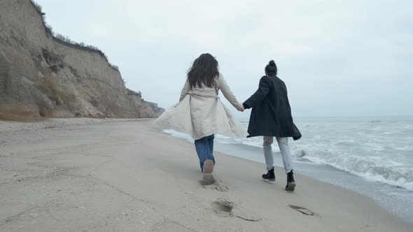 Happy Couple Run on the Wild Beach on Cloudy Sunrise