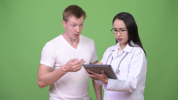 Young Asian Woman Doctor Giving Consultation To Young Man Patient