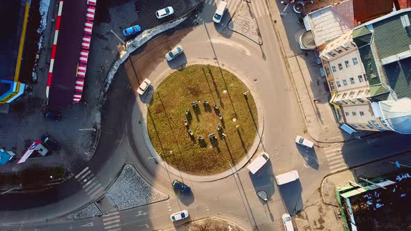 Aerial drone view of cars moving fast on a busy roundabout road.