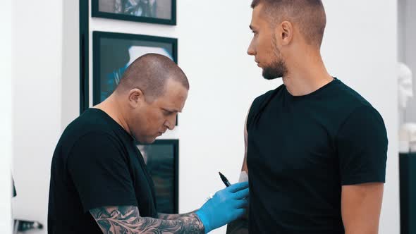 Male Tattoo Artist Tattooing a Client