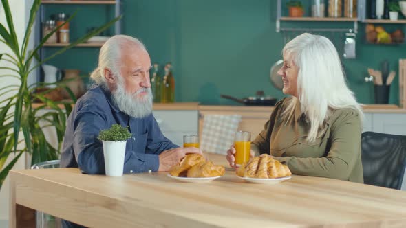 An Affectionate Elderly Couple Is Having Breakfast in The Cozy Kitchen