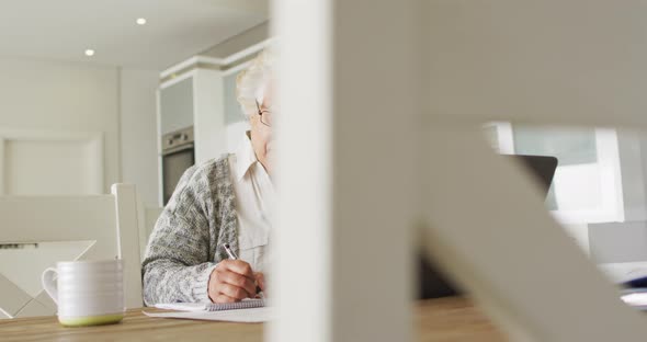 African american senior woman with laptop taking notes at home