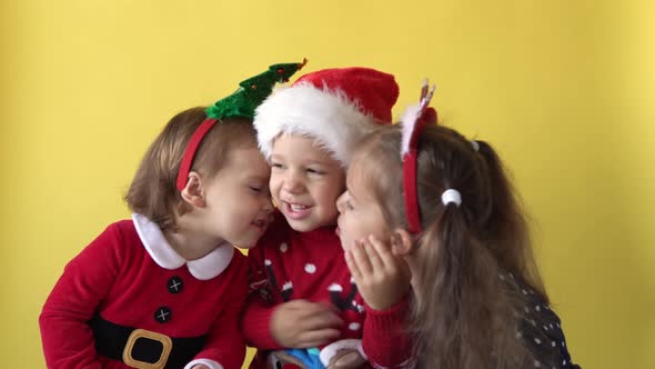 Emotion Cute Happy 3 Siblings Friends Baby Girl Boy Kissing Hug In Santa Suit Looking On Camera At