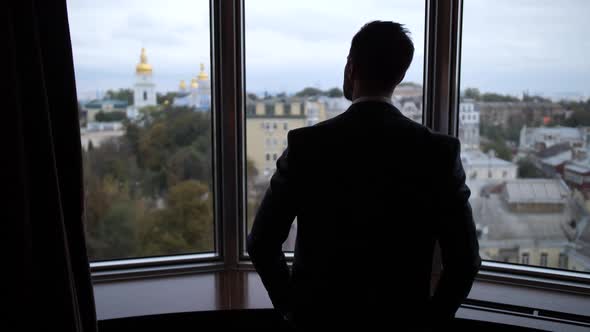 Silhoutte of Man Pulling Curtains in Hotel Room