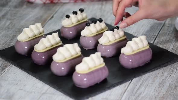 Confectioner decorates mousse cake with a blueberries Production of glazed desserts