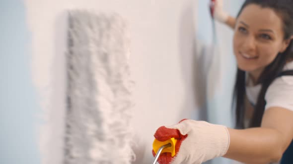 Happy Young Woman Painting Interior Wall with Paint Roller in New House