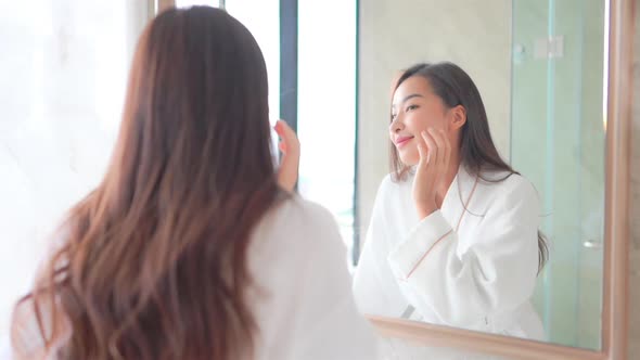 Young asian woman check her face on mirror