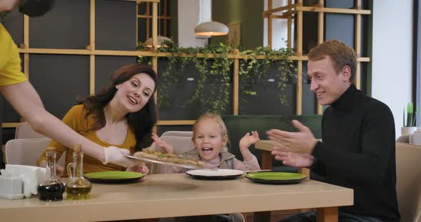 Happy Positive Man Woman and Girl Rejoicing Pizza in Restaurant