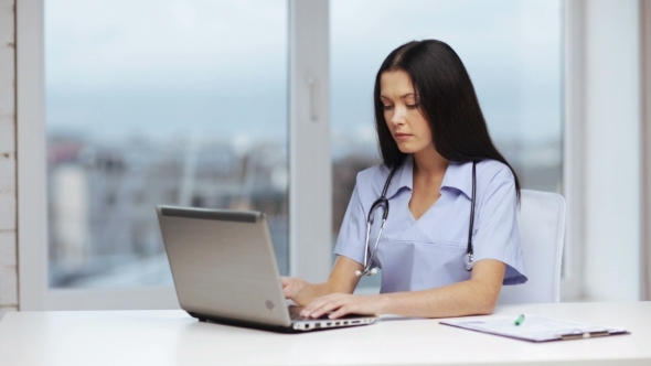 Doctor Or Nurse Typing On Laptop At Medical Office