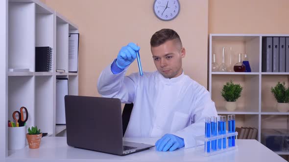 Scientist Works with Test Tubes at the Working Place