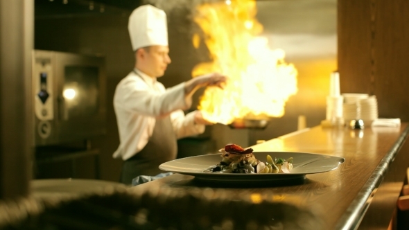 Male Chef Is Cooking Flambe In Restaurant Kitchen