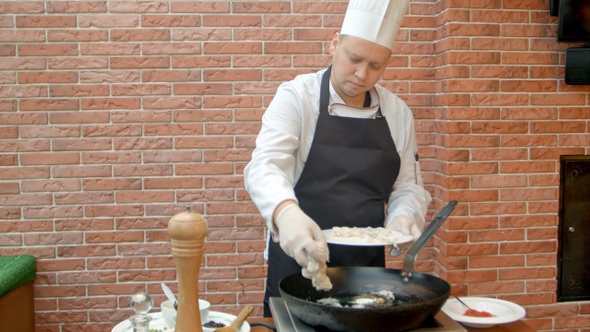 Chef putting fresh seafood to a pan