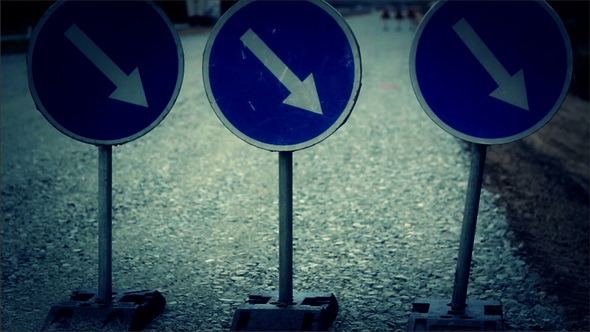 Down Right Road Sign Standing on Gravel Ground