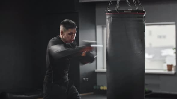 Athletic Young Man Boxer Hitting the Punching Bag