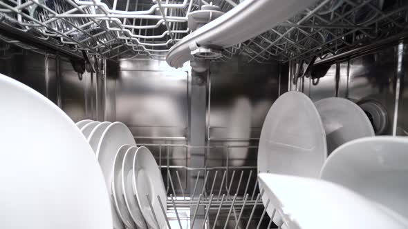 Backward Dolly Shot of Dishwasher Machine with Dishes and Silverware