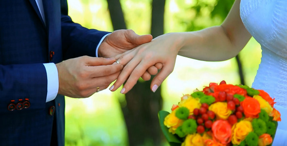 Groom Putting Wedding Ring on Finger of Bride