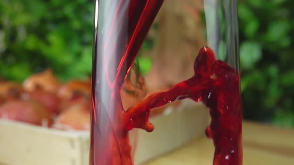 Closeup of Juice Flowing in a Glass Jug Next To the Box Full of Pomegranates
