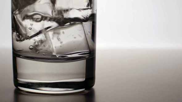 Clean Water Pours Into A Glass With Ice Cubes