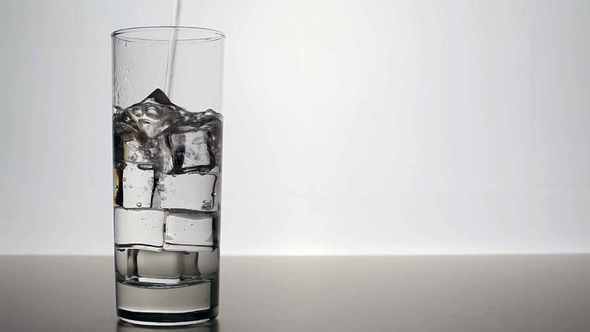 Clean Water Pours Into A Glass With Ice Cubes