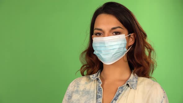 A Caucasian Woman Puts on a Face Mask Looks at the Camera Takes the Mask Off  Green Screen