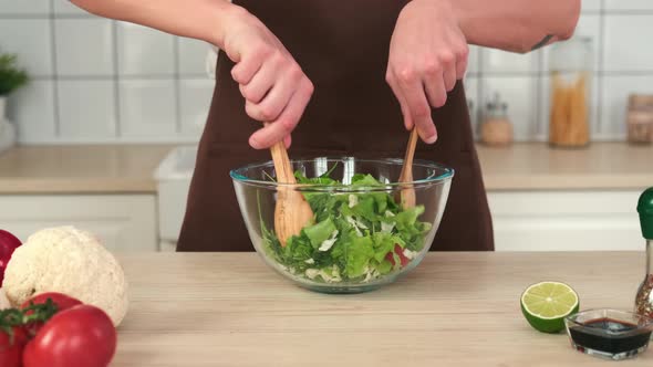 Man in Apron Stirring Vegan Salad in a Cup While Standing in the Kitchen